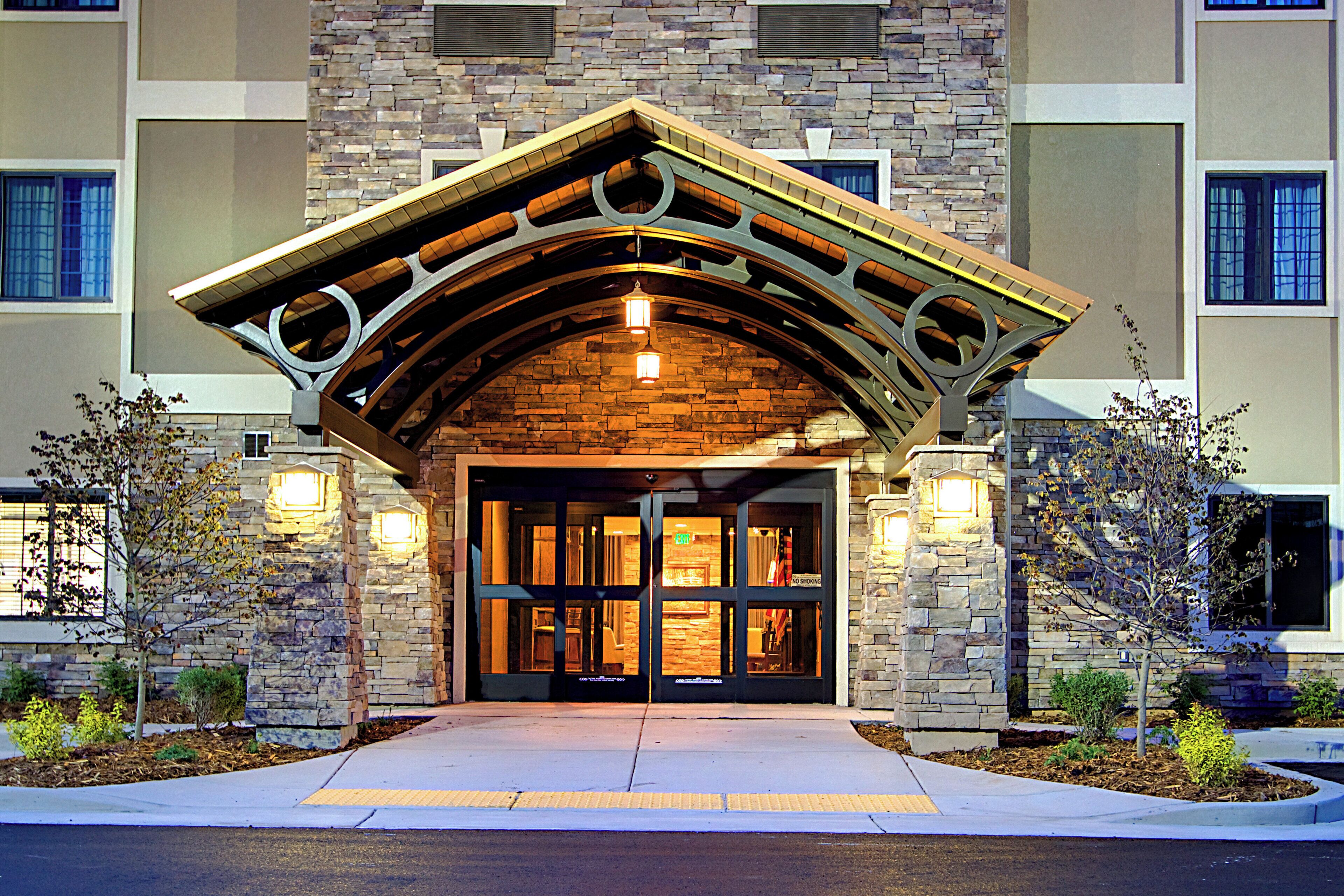 Une entrée d’immeuble avec une façade en pierre, une arche en bois et une rampe menant à la porte.