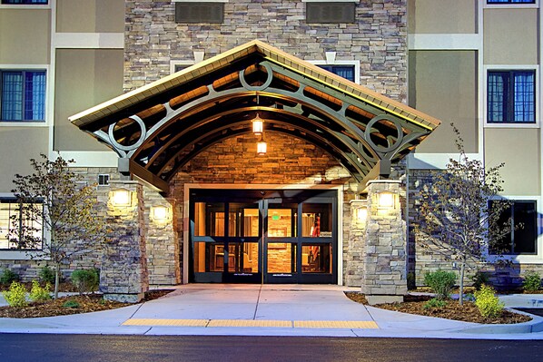 Una entrada de edificio con fachada de piedra, un arco de madera y una rampa que lleva a la puerta.