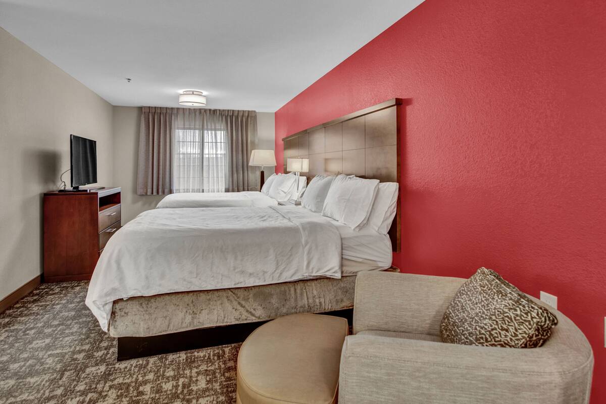 A hotel room with a large bed, a bedside table with a lamp, and a television on a stand.