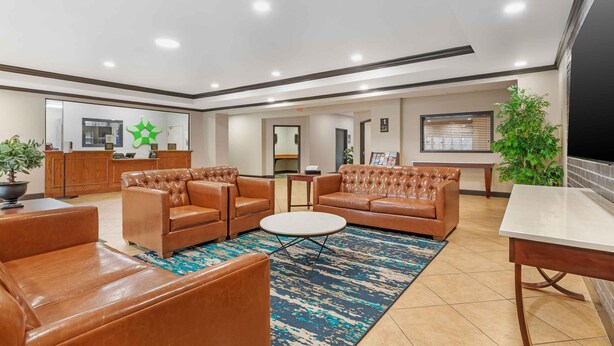 A lobby with leather sofas, a coffee table, a reception desk, and a large mirror.