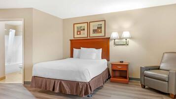 Una camera d'albergo con un letto, una sedia, un comodino e due lampade a parete.