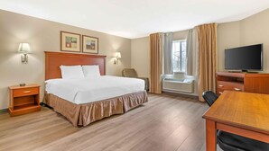 A hotel room with a bed, bedside tables, a desk, a television, and a window with curtains.