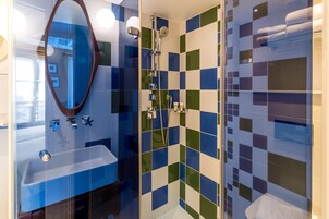 A modern bathroom with a large mirror, a sink, and a shower area.