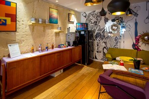 Una cucina moderna con mobili in legno, frigorifero integrato e macchina da caffè. È presente un tavolo da pranzo in legno con sedie e una piccola area salotto con un divano verde.