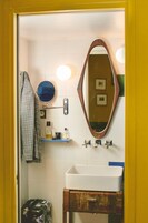 A bathroom with a white sink, a wooden vanity, a mirror, a towel rack, and a shower curtain.