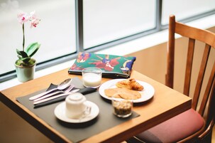 Una tavola imbandita per la colazione, con un croissant, un bicchiere di latte, una tazzina e un sottopiattino.