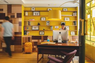 Een moderne werkplek met een houten bureau, een laptop en een gele koffer.