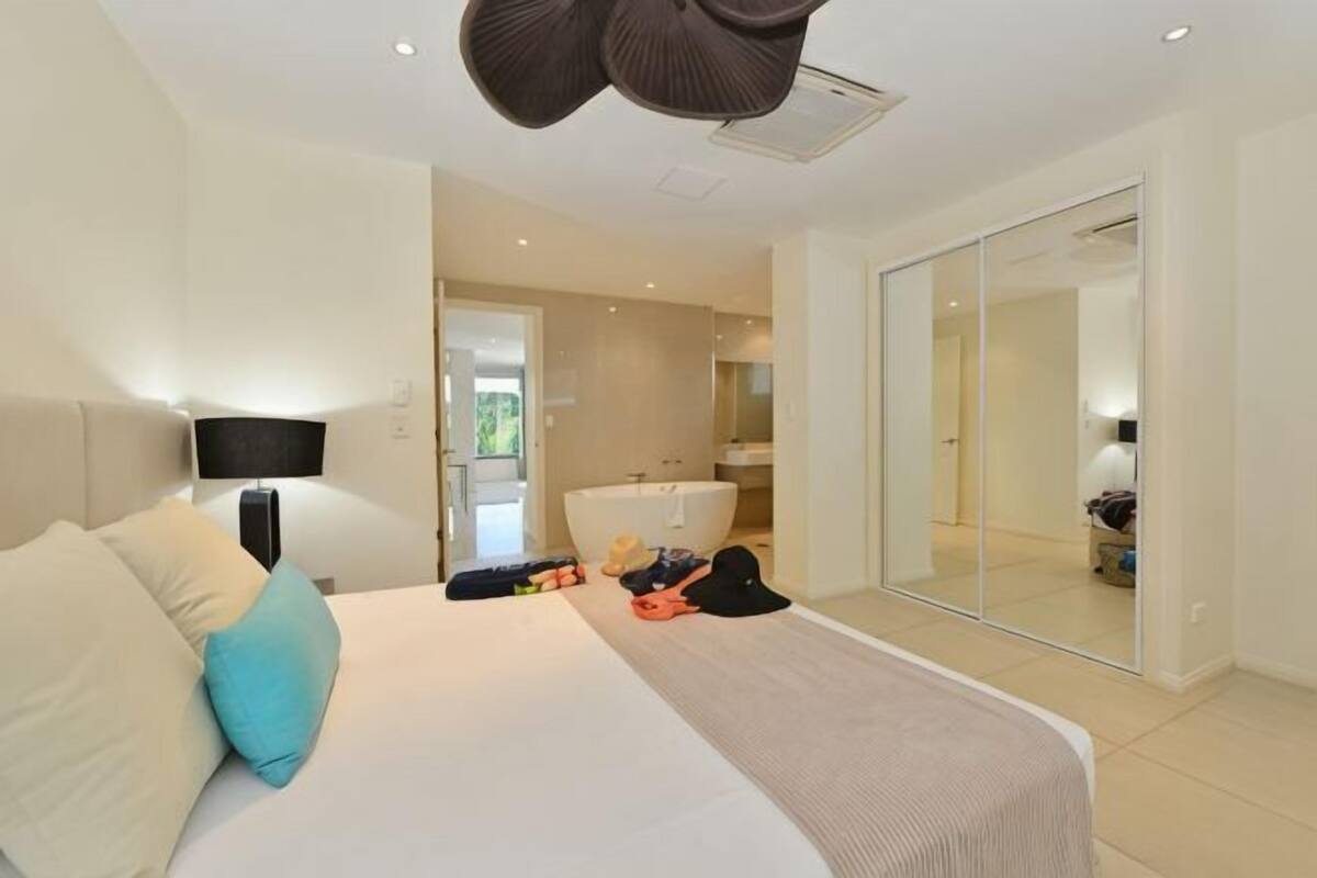 A bedroom with a bed, bedside table, lamp, and a large mirror.