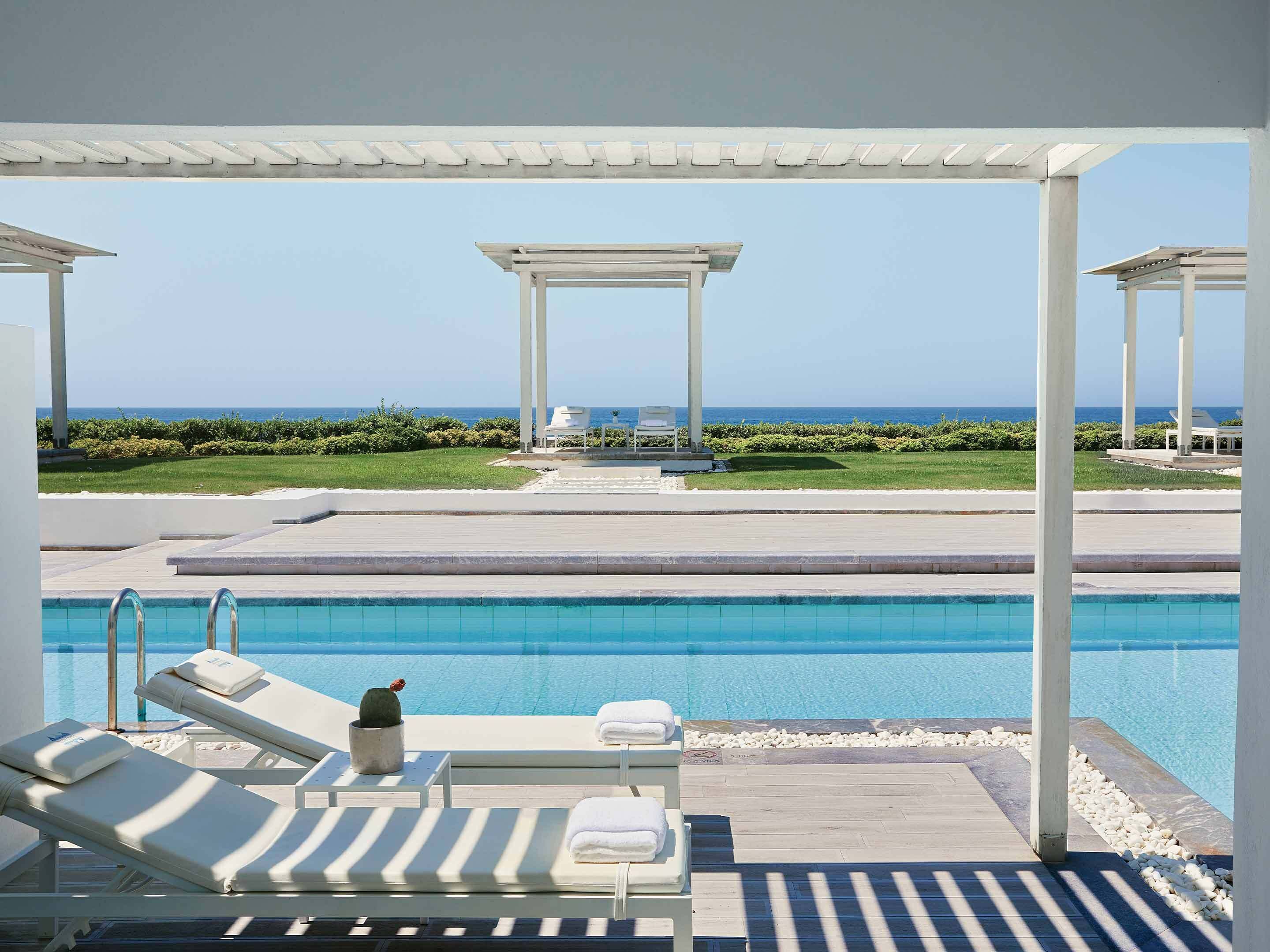 Zona de piscina con sillones de descanso y vista al océano.