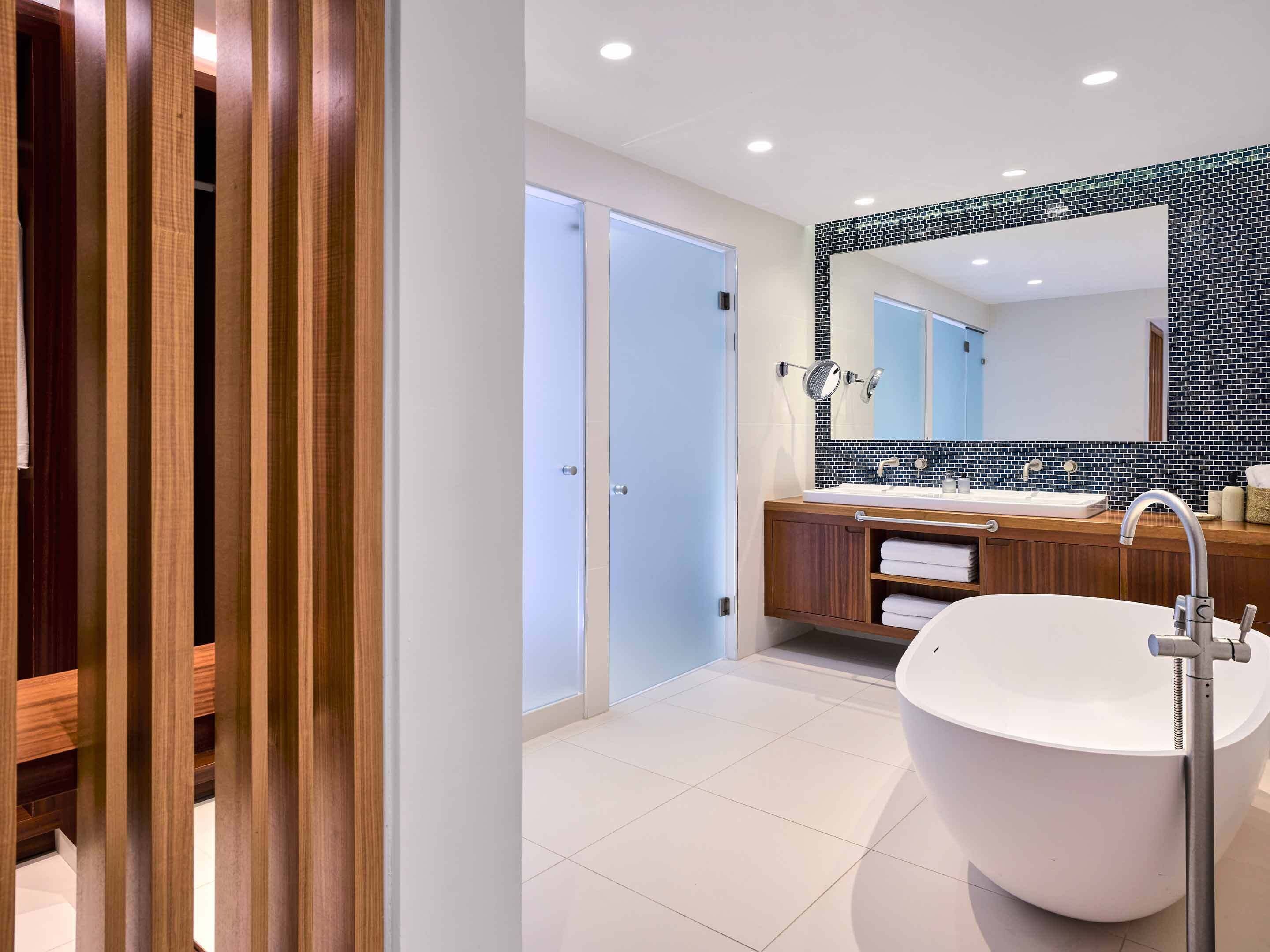 A modern bathroom with a freestanding bathtub, a large mirror, and a wooden vanity.