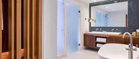 A modern bathroom with a freestanding bathtub, a large mirror, and a wooden vanity.