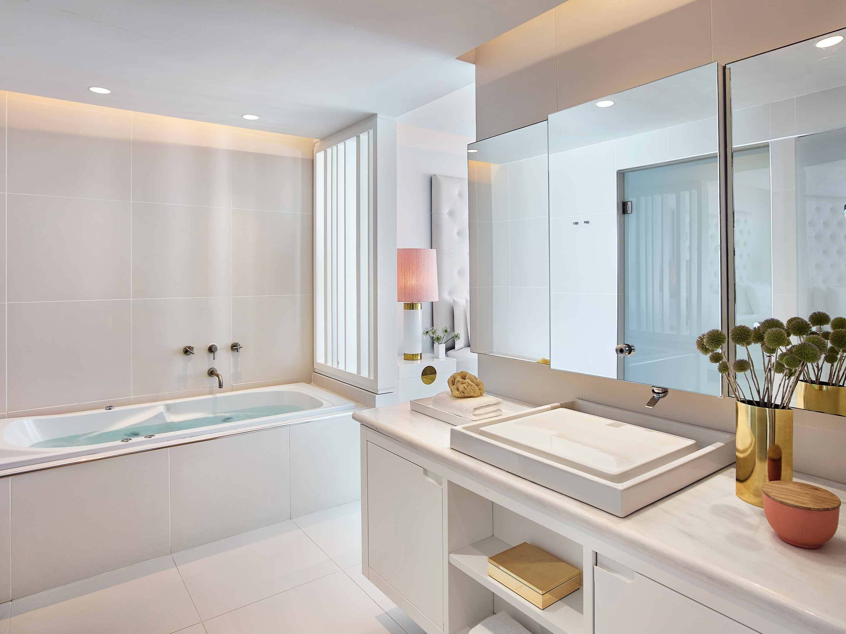 A modern bathroom with a bathtub, a large mirror, and a vanity with a sink.