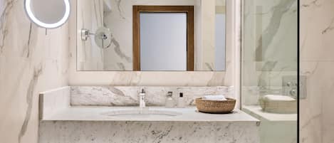 Un baño con un lavamanos de mármol, un espejo redondo y un espejo con marco de madera.