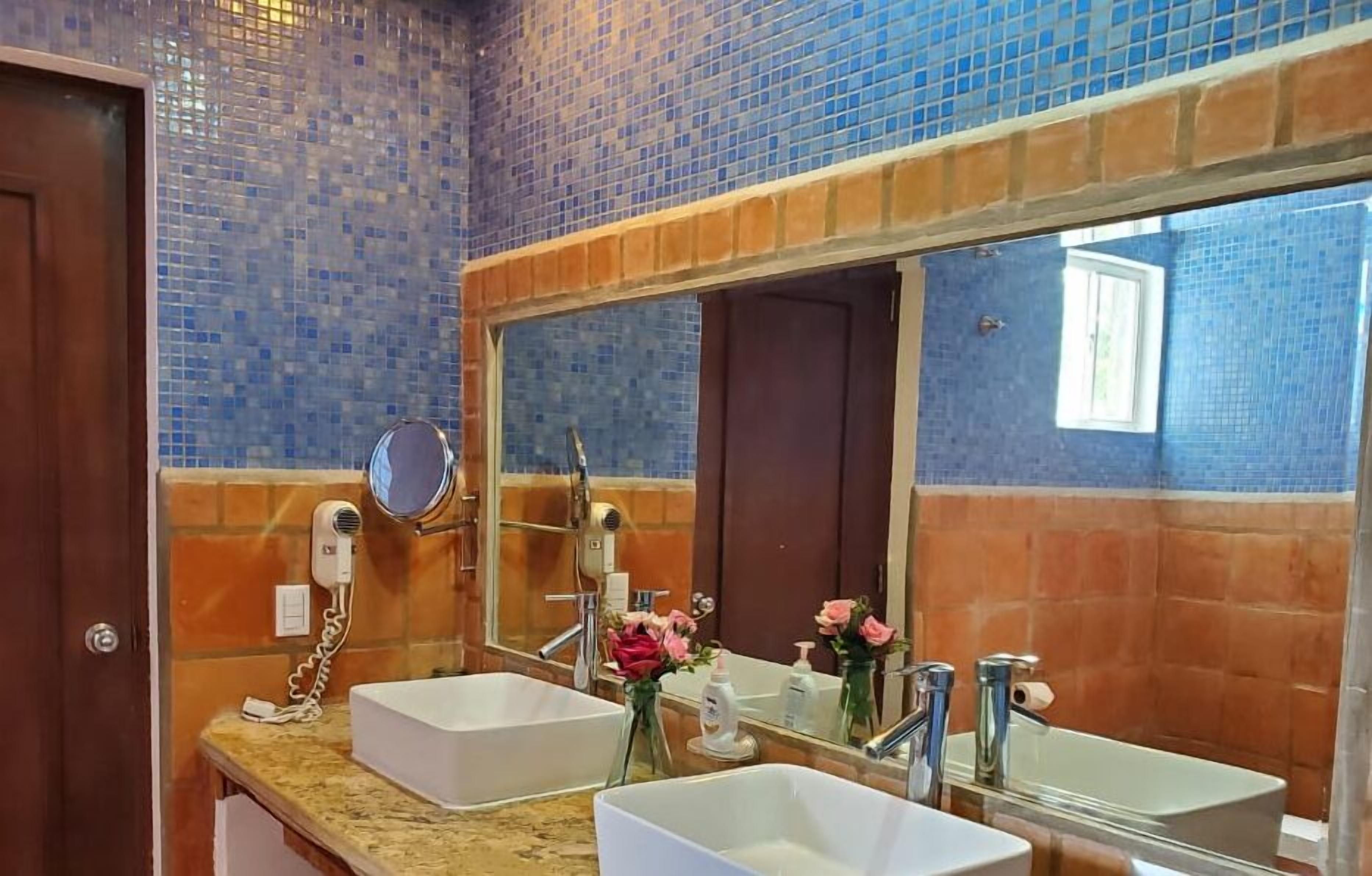 A bathroom with two sinks, a hairdryer, and a mirror.