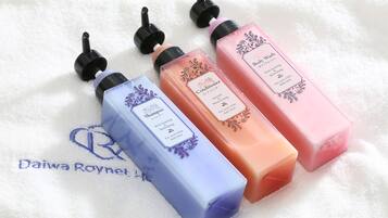 Four bottles of shampoo and conditioner on a white towel.