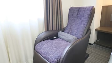 A reclining chair with a patterned fabric, positioned in a room with a carpeted floor and a wooden shelf.