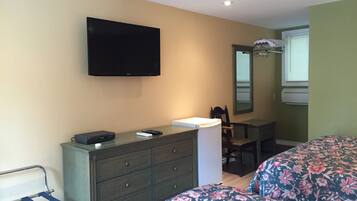 A bedroom with a bed, a dresser, a television, and a desk.