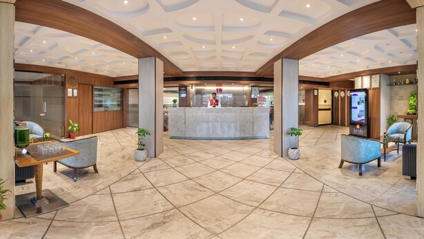 Un vestíbulo amplio con una recepción central, suelo de baldosas y detalles de madera.