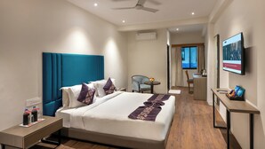 Una habitación de hotel moderna con una cama grande, un escritorio, una silla y un televisor.