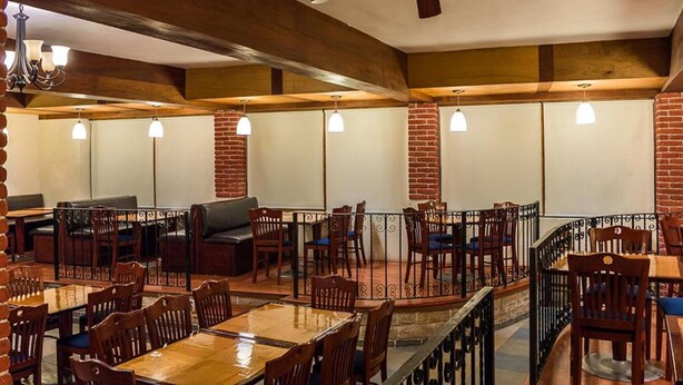 Un restaurante con paredes de ladrillo, mesas y sillas de madera.
