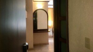 Un pasillo estrecho con una puerta a la izquierda y un espejo a la derecha.