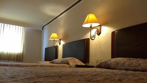 Una habitación de hotel con dos camas, cada una con cabecera y lámpara.