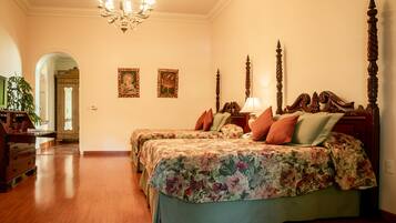 Quarto com duas camas, um candelabro e cabeceira de madeira.