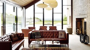 A spacious living room with a large window, leather sofas, and hanging paper lanterns. - Comwell Klarskovgaard (Korsor)
