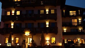 Un hôtel à plusieurs étages doté de balcons, une entrée principale ornée d’un lustre et une enseigne indiquant qu’il s’agit d’un hôtel.