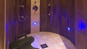 Un espace douche moderne au design incurvé, doté d’un banc et d’une pomme de douche fixée au mur.