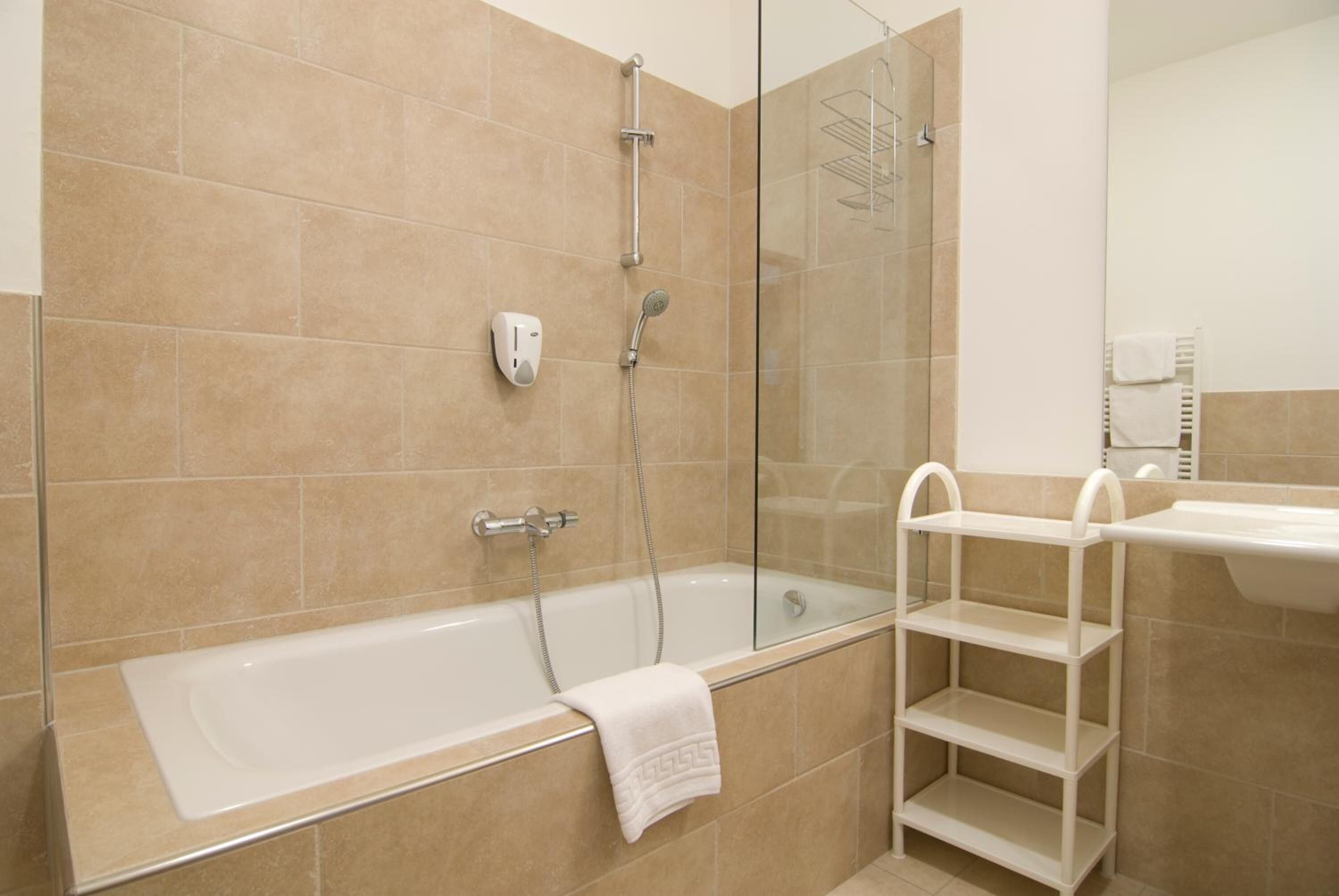 Un baño moderno con bañera, ducha y zona de ducha con mampara de vidrio.