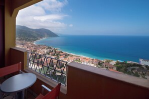 Balcón con mesa y sillas que da a un pueblo costero y al mar.