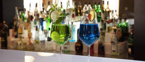 Dos cócteles sobre la barra, con varios botellas al fondo.