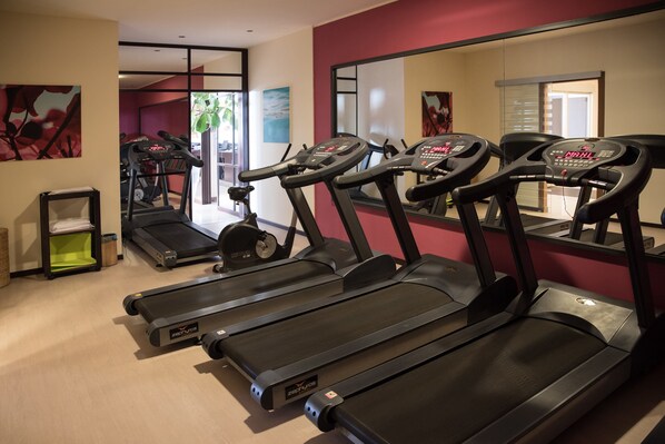 A gym with treadmills, exercise equipment, and a mirror reflecting the space. - Hotel Avalon Sikanì (Gioiosa Marea)