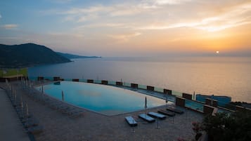 Una piscina al aire libre, sombrillas, sillones reclinables de piscina