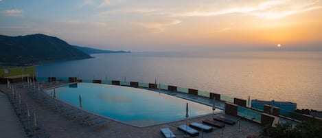 Una piscina al aire libre, sombrillas, tumbonas