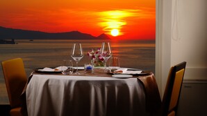 A table set for two with a view of a sunset over water.
