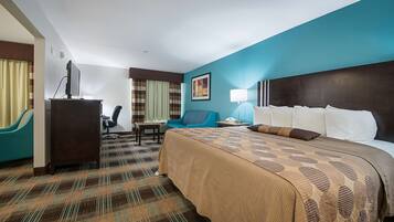 Habitación de hotel con una cama grande, un escritorio, una silla y un televisor.