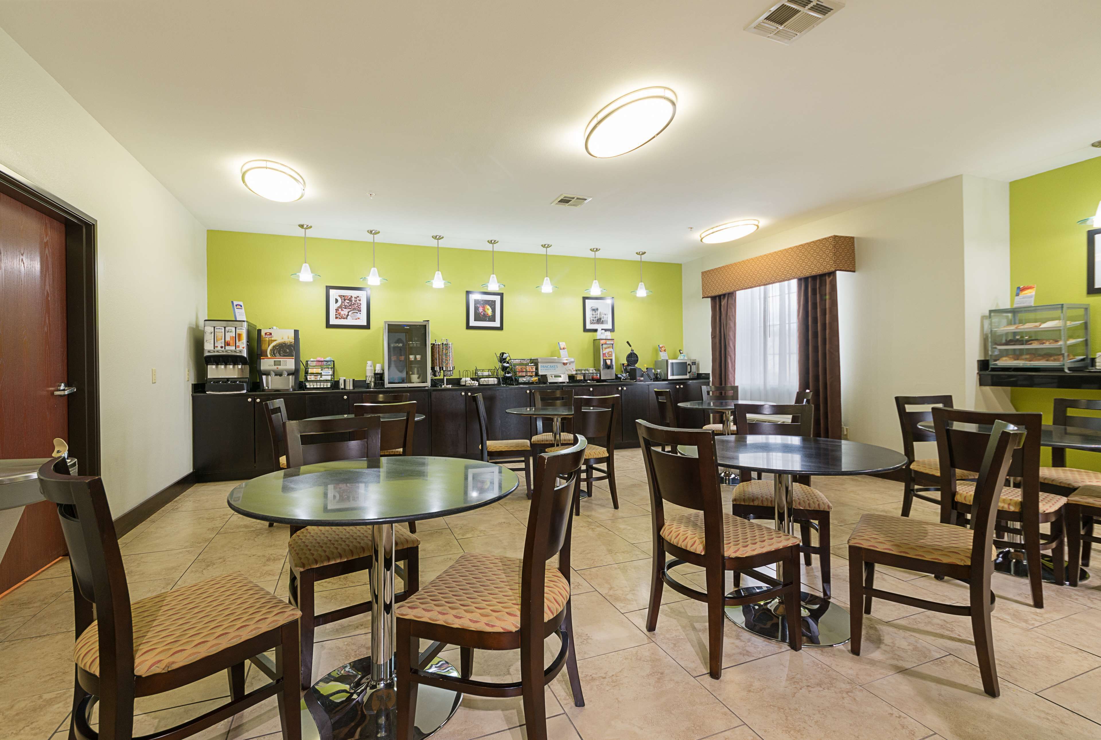A restaurant with multiple tables and chairs, a counter with a menu, and framed pictures on the wall.