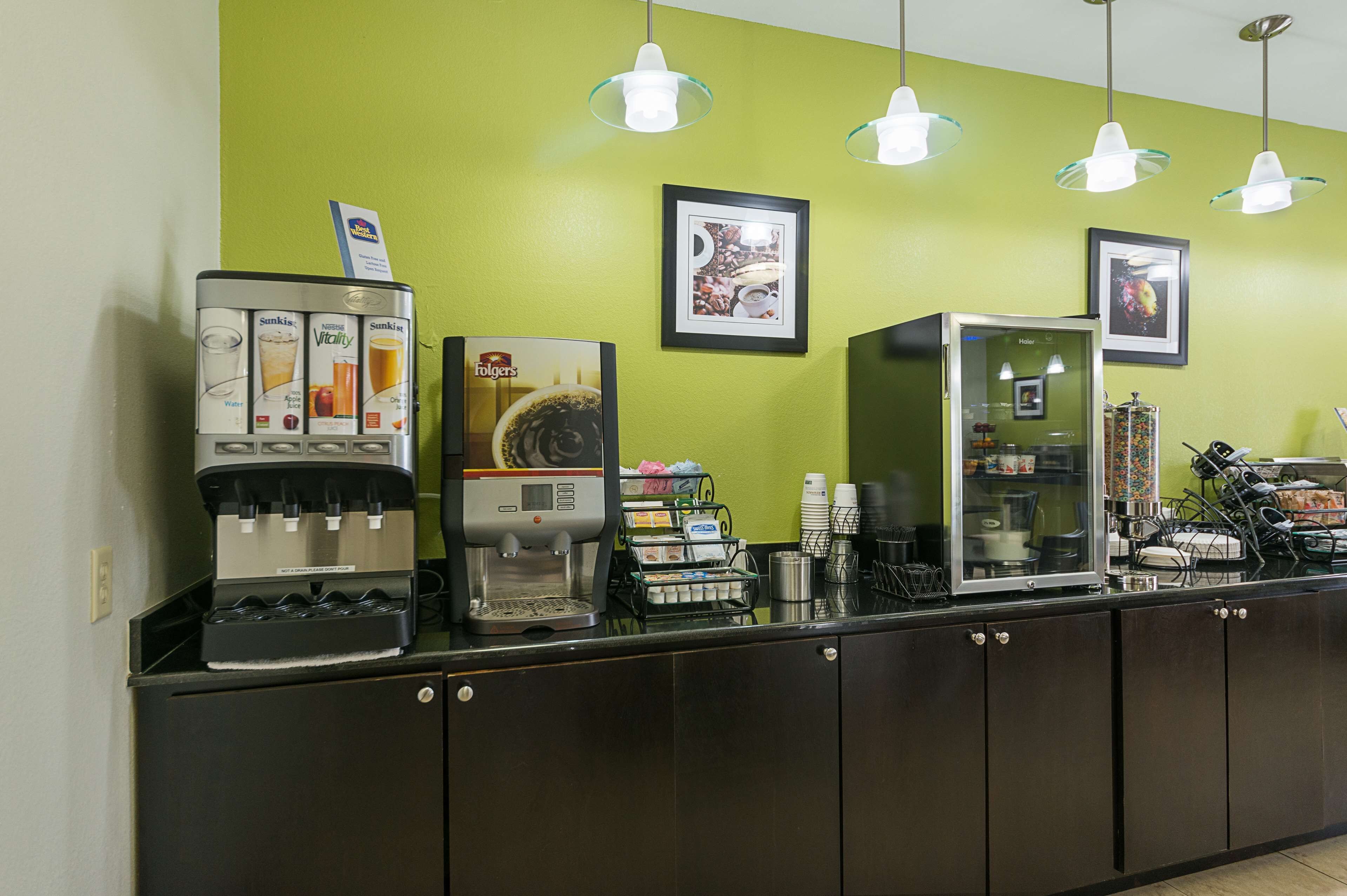 Una estación de café con varios dispensadores de bebidas, una máquina de café y un refrigerador expositor.