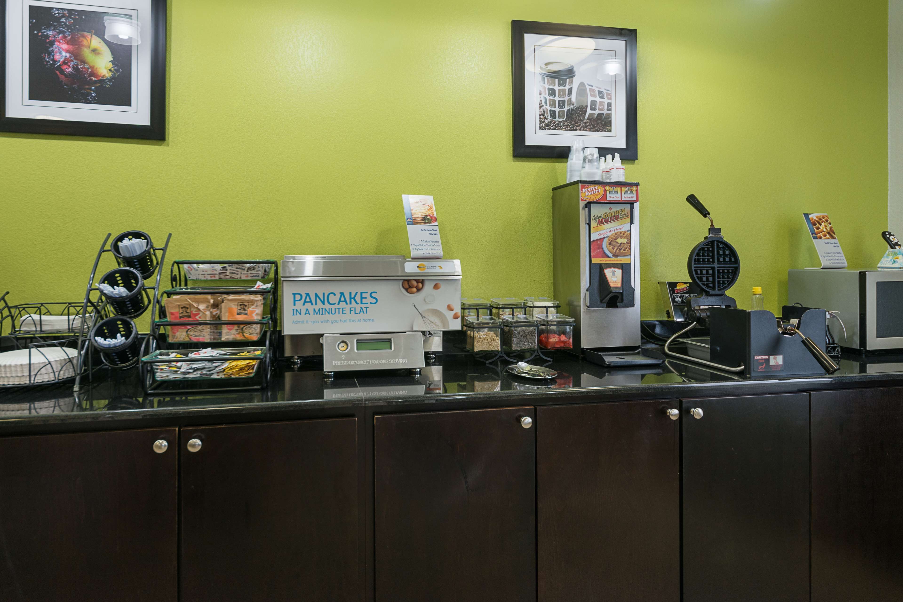 A breakfast counter with a waffle maker, a coffee machine, and various food items.