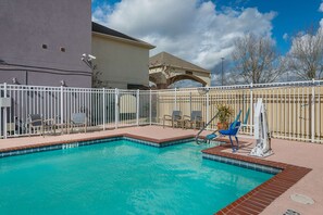 A swimming pool with a white fence, lounge chairs, and a water fountain. - Best Western Plus Deridder Inn & Suites (DeRidder)