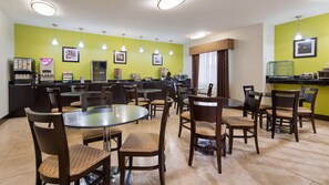 A hotel dining area with multiple tables and chairs, a coffee machine, and a refrigerator. - Best Western Plus Deridder Inn & Suites (DeRidder)
