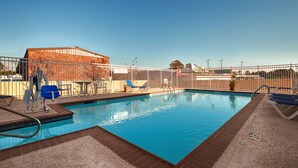 A swimming pool with a fenced area, lounge chairs, and a lifeguard on duty.