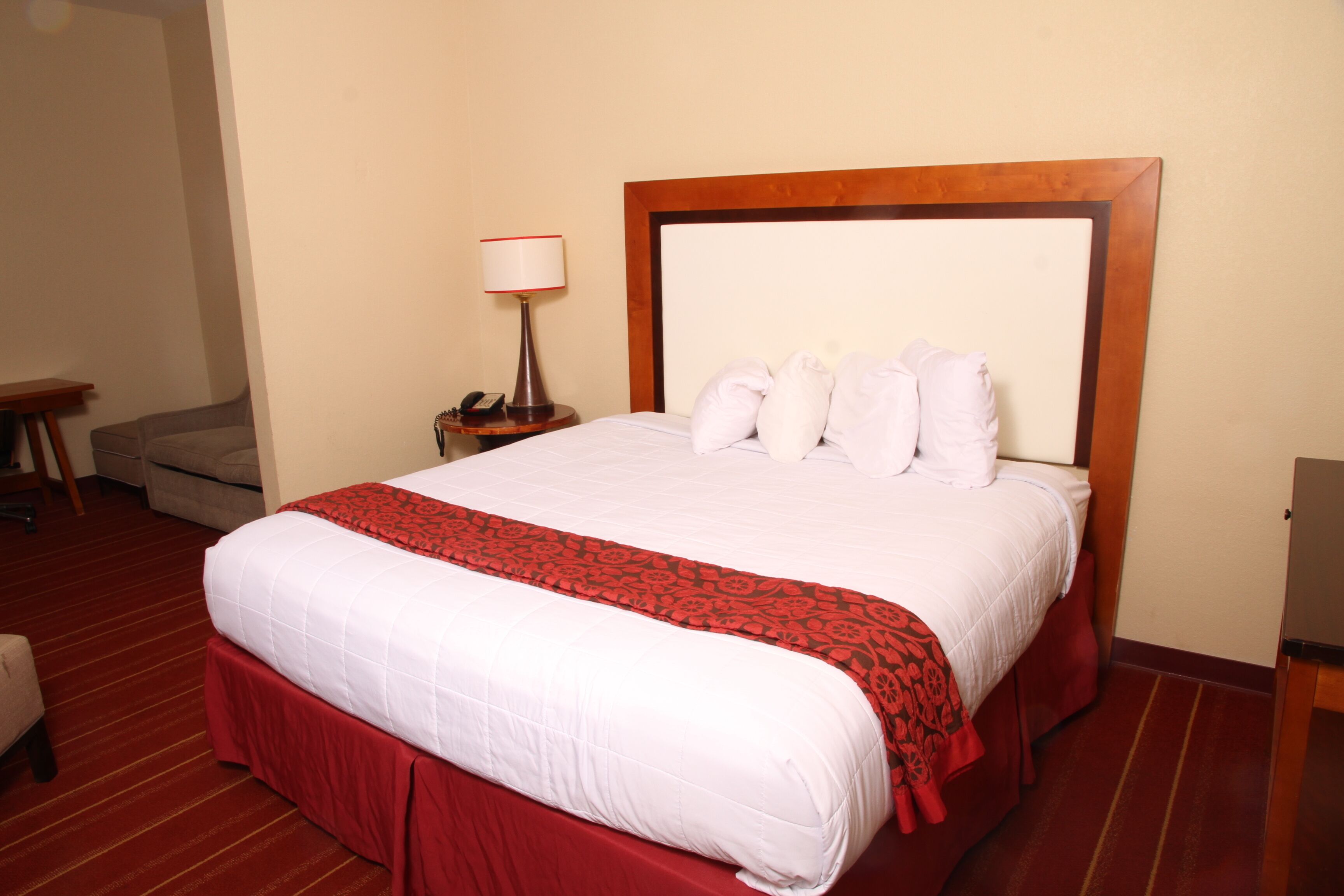 A hotel room with a large bed, a bedside table with a lamp, and a chair.