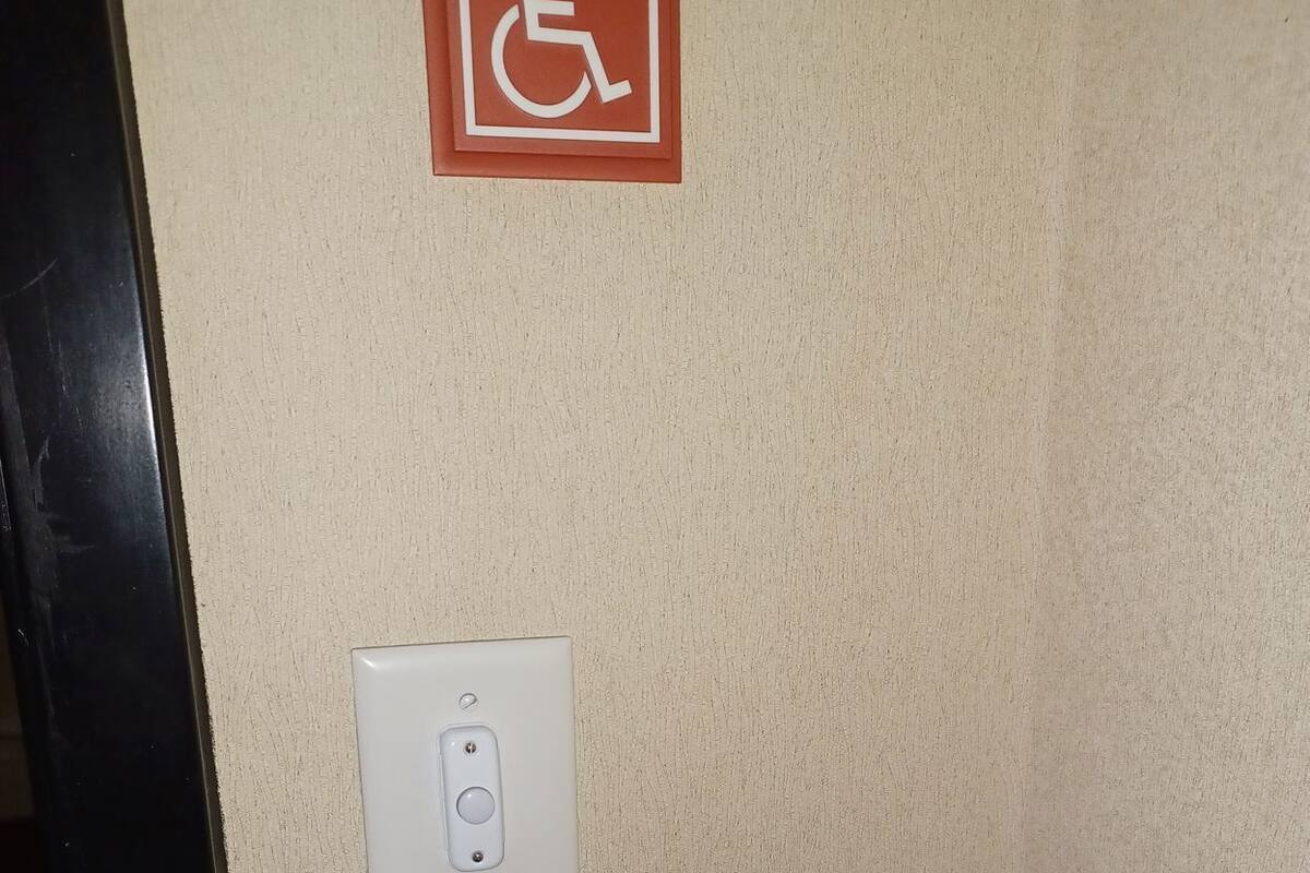 A wall with a handicap sign and a light switch.