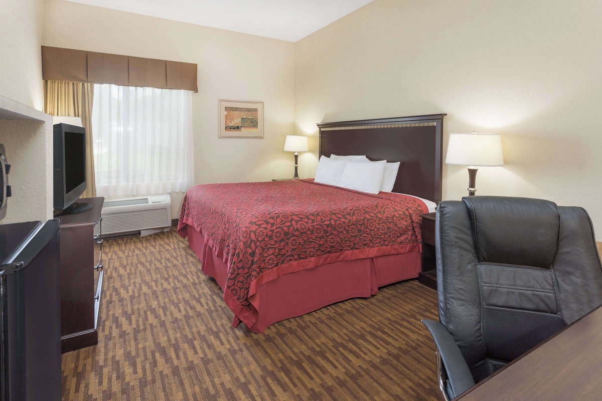 A hotel room with a bed, two bedside lamps, a television, a desk, and a chair.