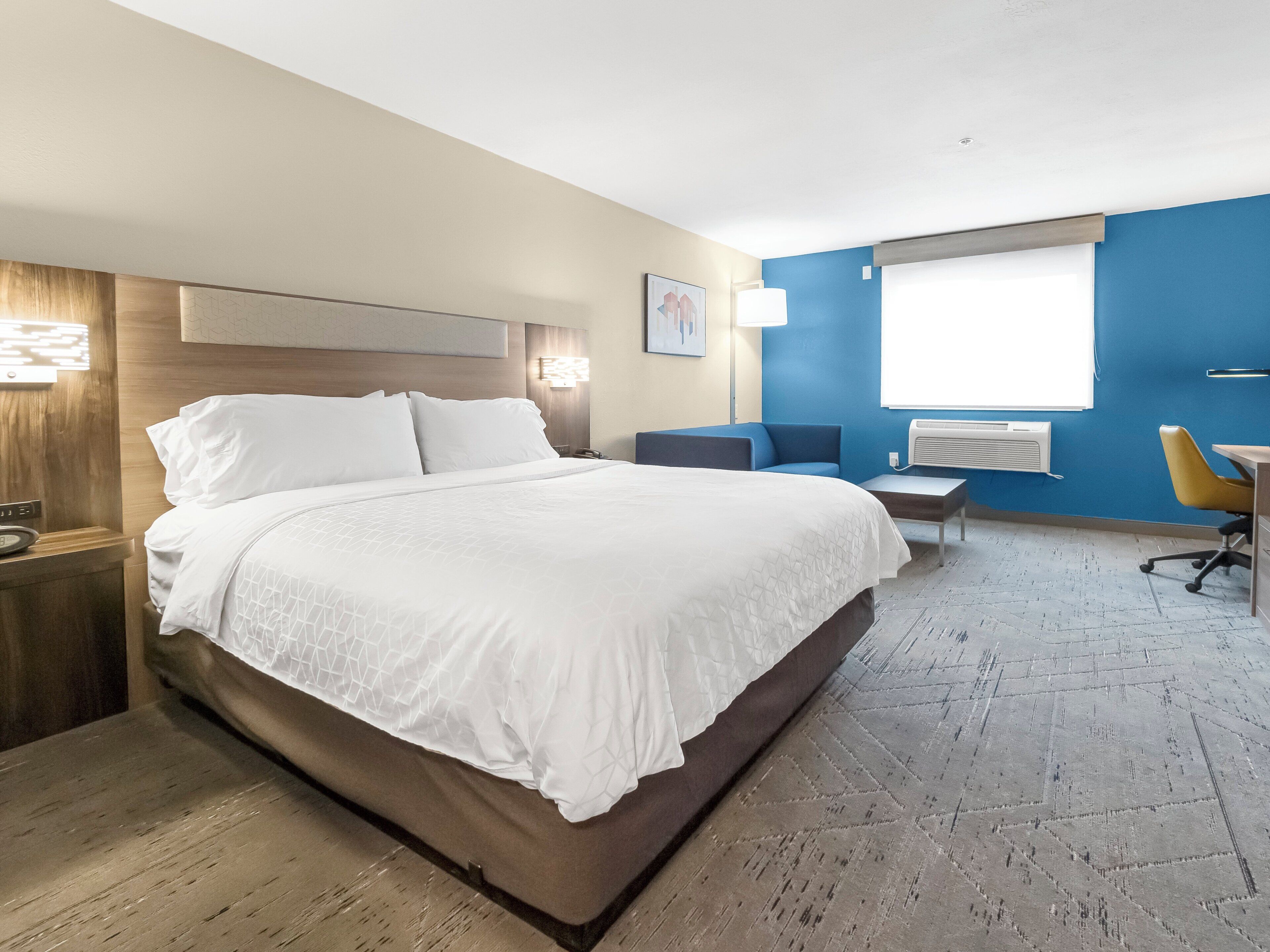 Een hotelkamer met een groot bed, een bureau, een stoel en een raam.