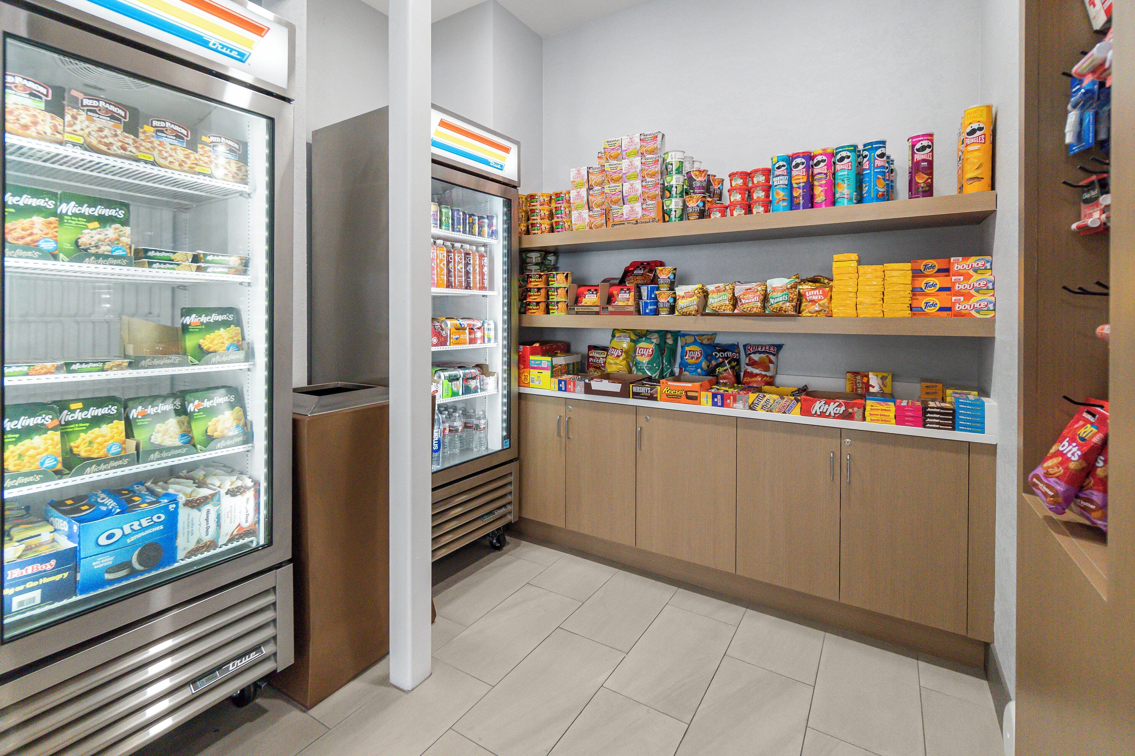 Interior de um supermercado, com seções refrigeradas e prateleiras repletas de diversos produtos alimentícios.