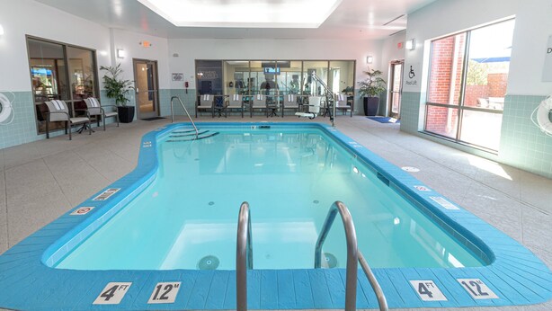 An indoor swimming pool with clear water, marked depth indicators, and a pool lift. - Holiday Inn Express Leland - Wilmington Area by IHG (Leland)